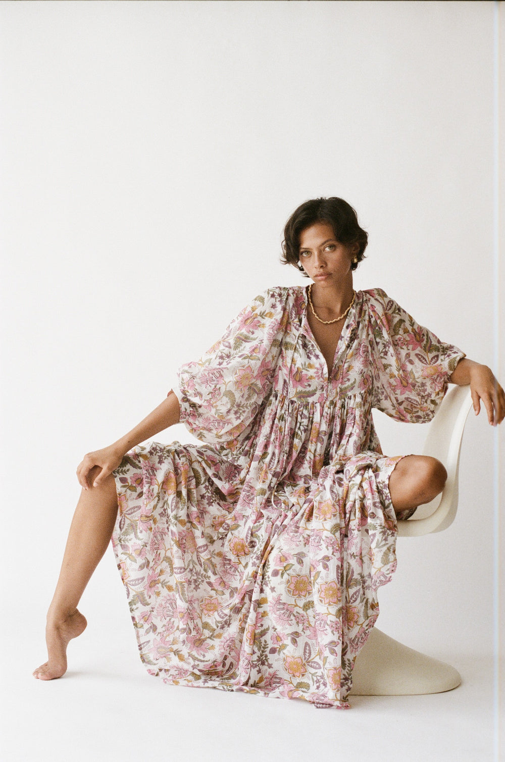 Daughters of India Kyra Maxi Dress in Fuchsia Bloom — studio seated on chair, flowing skirt draped, V-neckline
