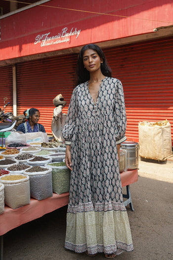 Bhoomi Maxi Dress Onyx — full length front view at Indian spice market, onyx hand block print maxi dress with V-neckline and tiered hem, colourful spice stall India | Daughters of India