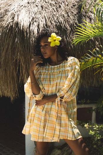 Freya Dress Honeycomb Plaid — tropical thatched setting, model with hibiscus flower, off-shoulder billowy sleeves, handloom woven honeycomb plaid with embroidered neckline, artisan boho dress | Daughters of India